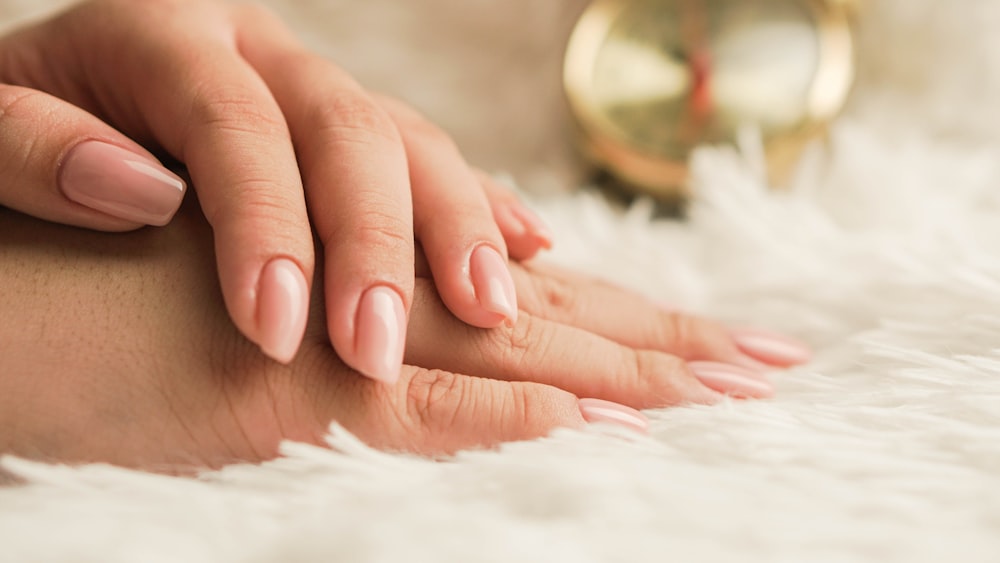 Blush almond nails, one hand resting across the other on white fur