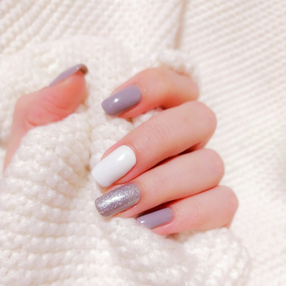 Grey, white and glitter nails held against a cream cable knit