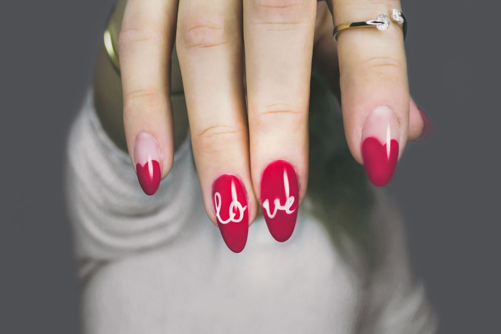Deep pink nails with white lettering painted across two fingers